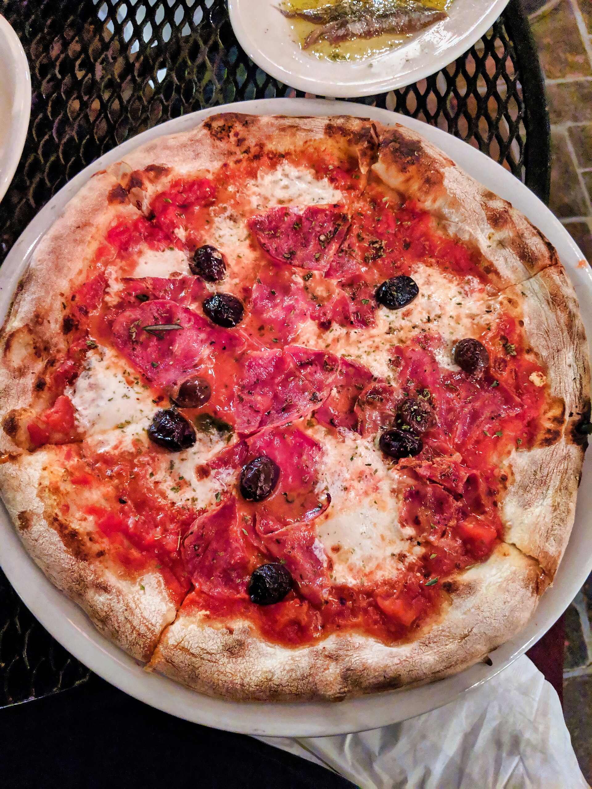 A blistered wood-fired pizza with tomato, mozzarella, salami and black olives at Pizzeria Bianco in Phoenix